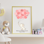 Close-up of personalized pink elephant guest book with signed fingerprint balloons, styled on a baby shower gift table.