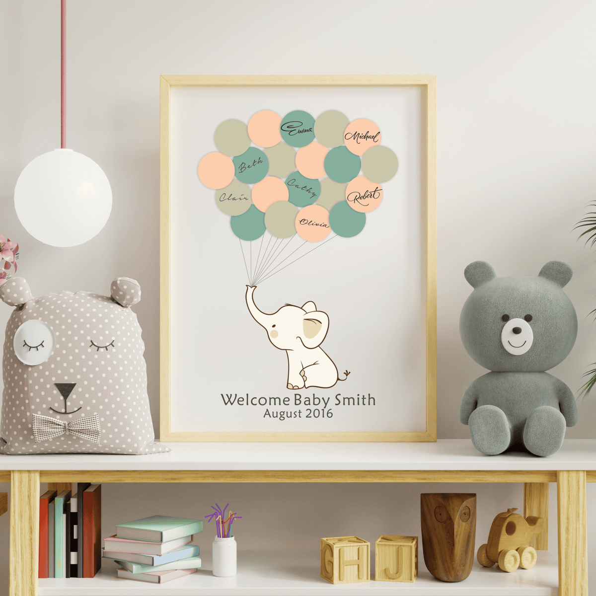 Personalized elephant baby shower guest book in a white frame, featuring multicolored balloon prints and styled on a modern nursery shelf.