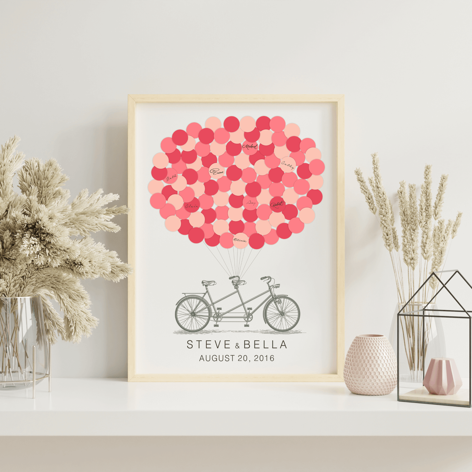 Framed tandem bike signature balloon guest book displayed at a wedding reception table with flowers and candles