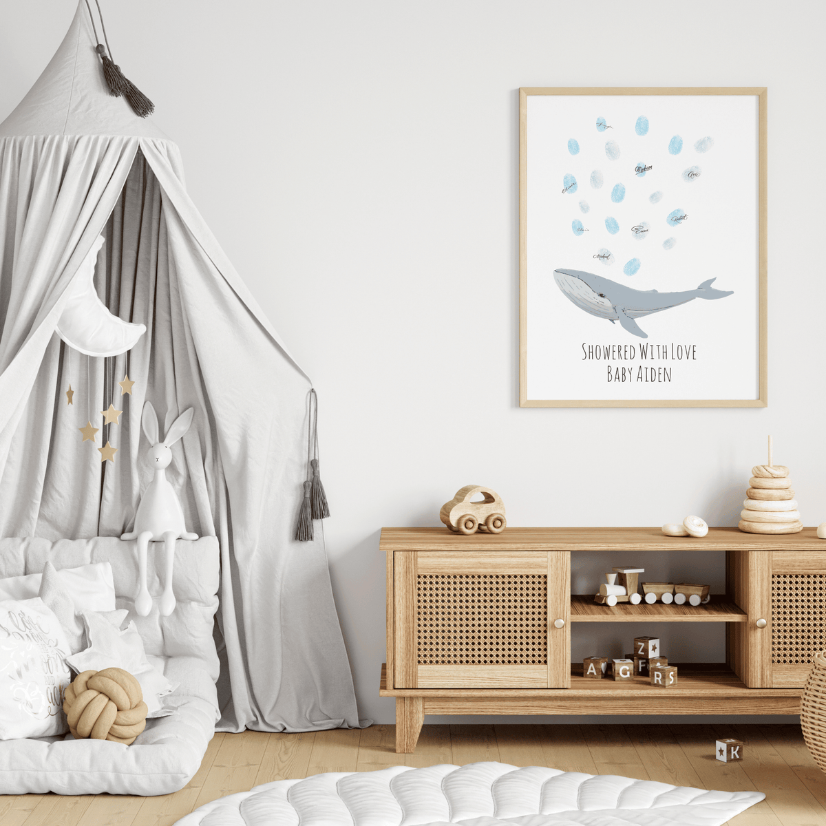 Whale baby shower fingerprint guest book with pale blue thumbprints displayed on a nursery wall
