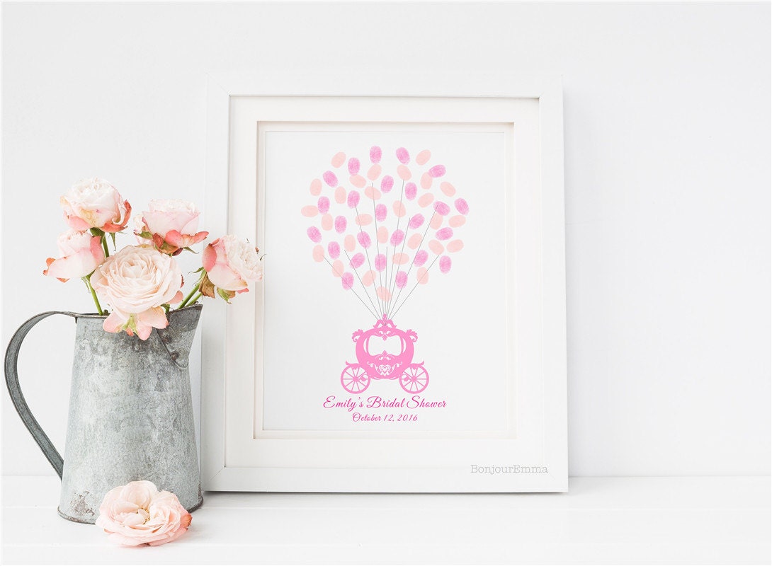 Close-up of framed princess fingerprint guest book on a dresser with wedding photos and soft pink accents.